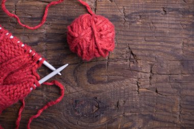 Ball of wool and knitting needles on a wooden background clipart