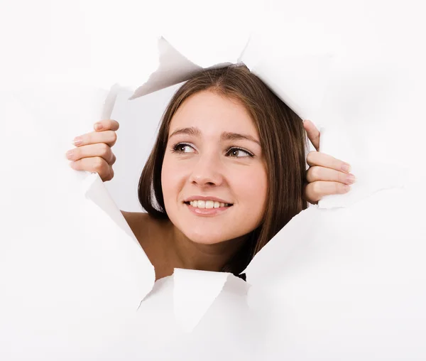 The girl spies through a hole in a paper. — Stock Photo, Image