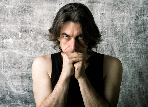 Dramatic portrait of serious man against an old wall.