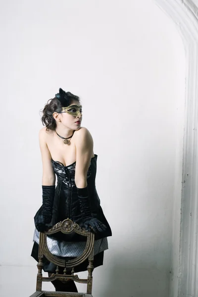 En elegant ung kvinna i maskeraddräkter i retro inredning. — Stockfoto