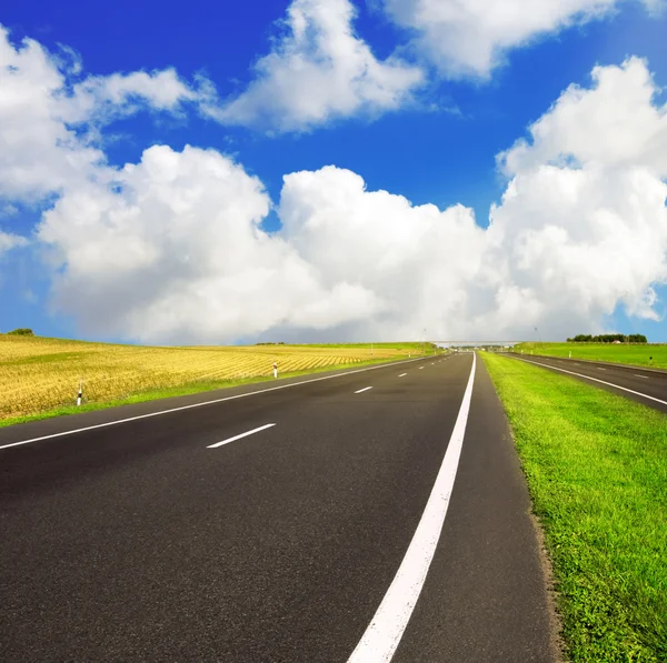 Asfaltové silnici přes modré oblohy — Stock fotografie