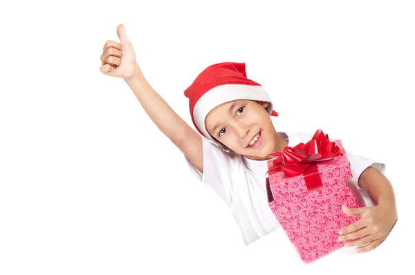 Мальчик в рождественской красной шляпе показывает большие пальцы вверх — стоковое фото