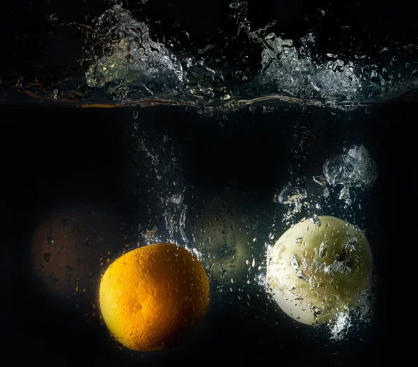 Gelber Apfel und Orange im Wasserspritzer — Stockfoto