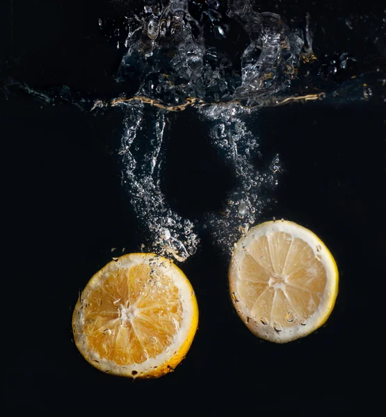 stock image Half lemon and orange in water splash