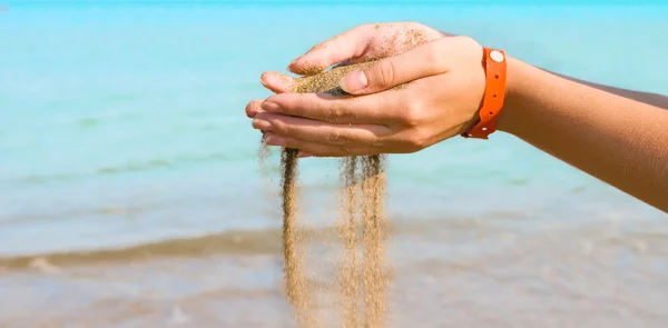 Chute de sable dans les mains de la femme sur la mer — Photo