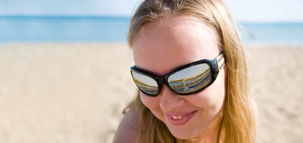 Woman wearing a pair of sunglasses reflecting the beach. — Stock Photo, Image