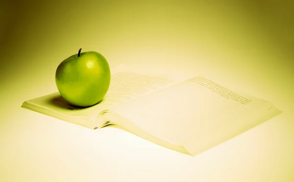 Ett grönt äpple och bok — Stockfoto