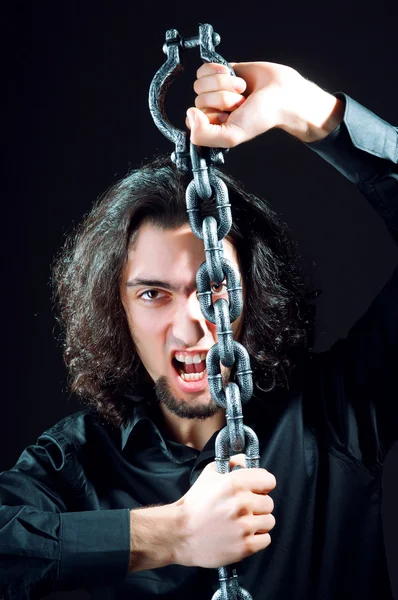 Человек прикован цепями в темной комнате — стоковое фото