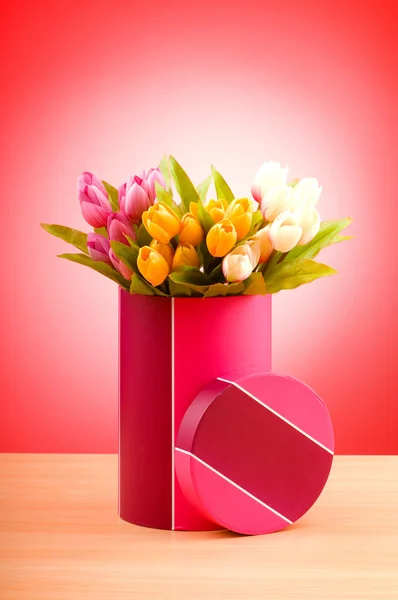 Caja de regalo y tulipanes contra el fondo degradado —  Fotos de Stock