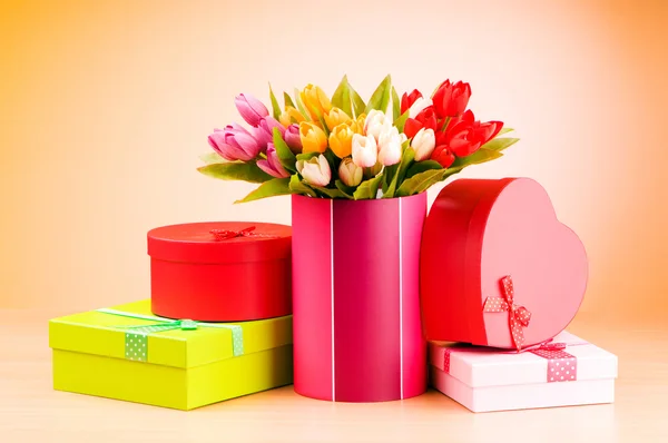 Caja de regalo y tulipanes contra el fondo degradado — Foto de Stock