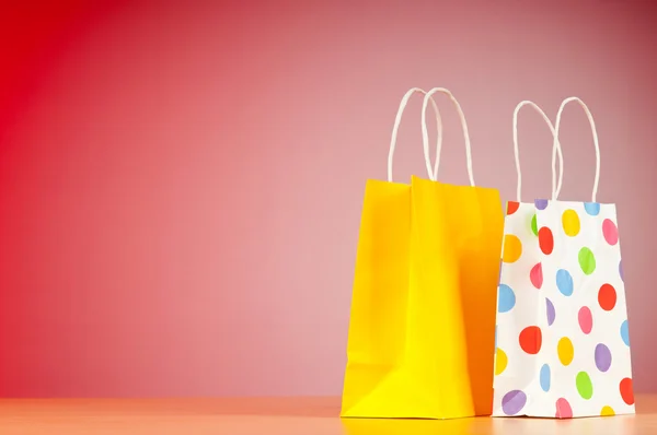 stock image Colourful paper shopping bags against gradient background