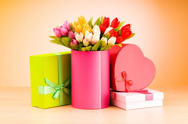 Dárkové a tulipány proti barevných přechodů — Stock fotografie