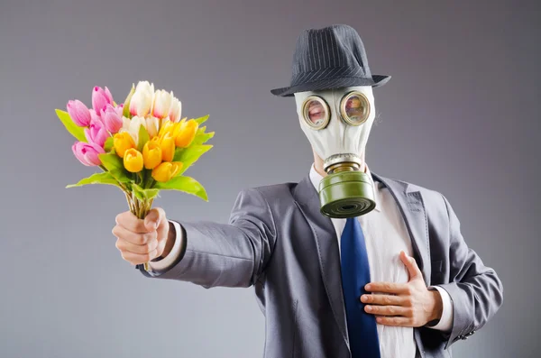 Zakenman met gas masker en bloemen — Stockfoto