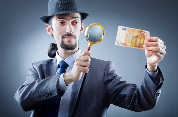 Детектив смотрит на фальшивые деньги — стоковое фото