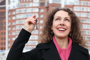 Young girl with key in hand looks upwards against many-storeyed clipart