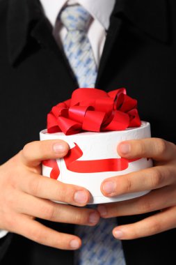 Businessman with gift box in hands clipart