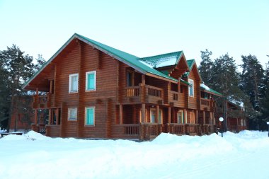 Wooden houses in winter forest clipart