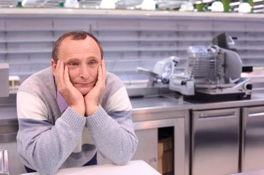 Bored seller in shop with empty shelves and counters clipart