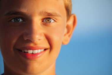 Smiling teenager boy against sea clipart