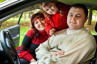 Married couple and little girl sit in car in park clipart