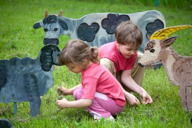 The girl and the boy feed a wooden animals clipart