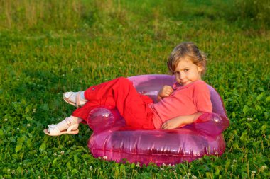 Young model sits in inflatable armchair outdoors clipart