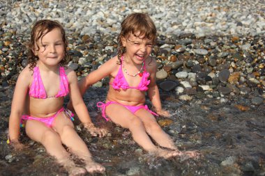 Two little girls sit ashore in water clipart