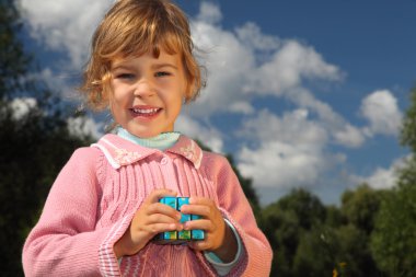 Little girl with magic cube outdoor in summer clipart