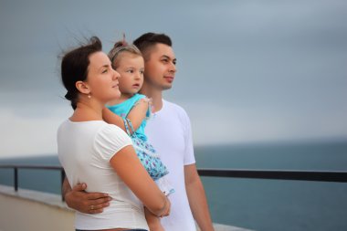 Young man and beautiful woman protects little girl from wind on clipart