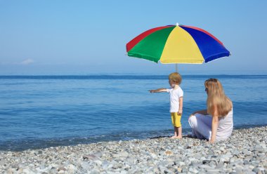 pebble Beach çok renkli şemsiye altında çocuk ile anne