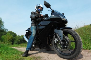 Motorcyclist standing on country road, bottom view clipart