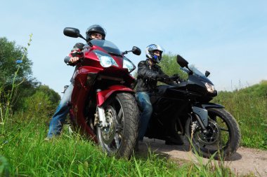 Two motorcyclists standing on country road, bottom view clipart