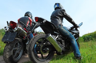 Two motorcyclists standing on country road, back view clipart