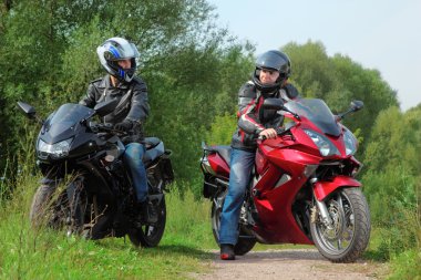 Two motorcyclists standing on country road looks on each other clipart