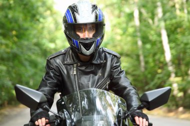 Motorcyclist goes on road, front view, closeup clipart