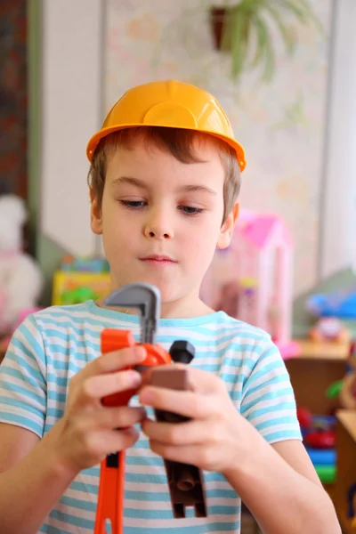 Хлопчик в пластиковому шоломі з іграшковими інструментами — стокове фото