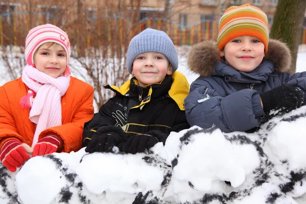 Трое детей на стене снежной крепости во дворе — стоковое фото