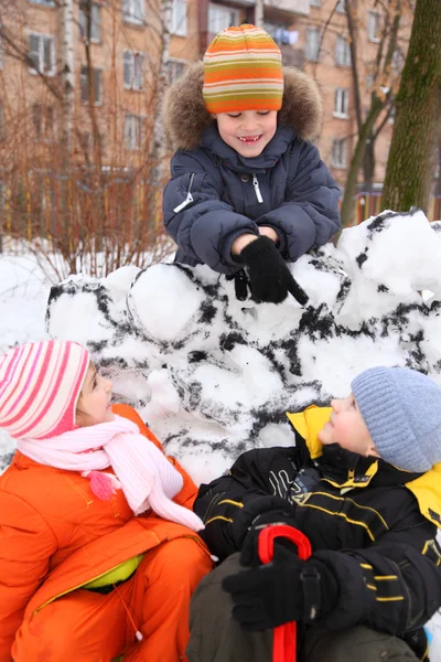 Tres niños en la fortaleza de nieve en el patio — Foto de Stock