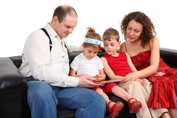 Dzieci z rodzicami poczytać książkę na kanapie — Zdjęcie stockowe