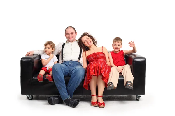 Pais com crianças sentam-se no sofá de couro preto — Fotografia de Stock