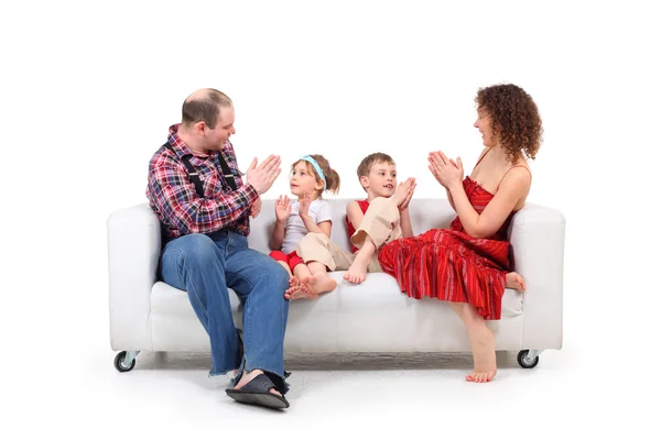 Os pais brincam com crianças sofá de couro branco — Fotografia de Stock