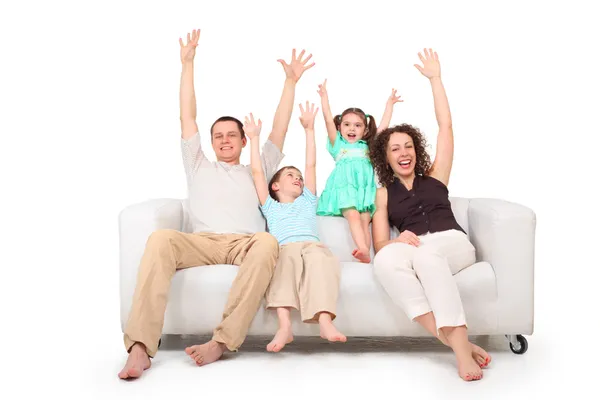 Pais e crianças com as mãos levantadas no sofá de couro branco — Fotografia de Stock