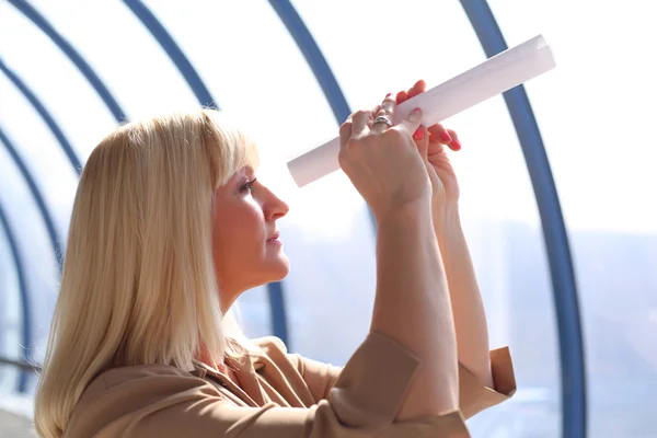 Empresária de médio porte olha em tubo de papel — Fotografia de Stock
