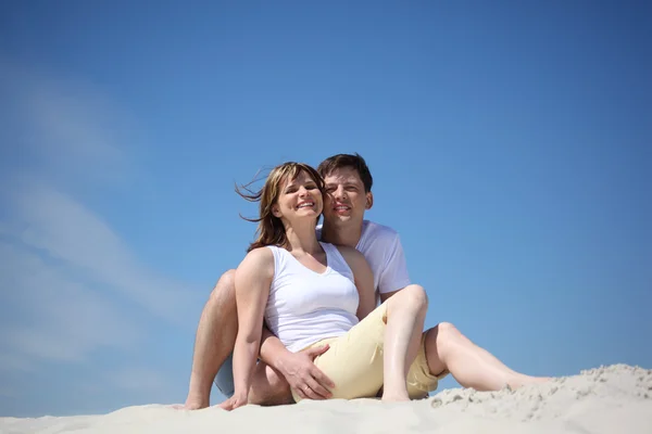 Улыбающаяся пара в белых рубашках на пляже — стоковое фото