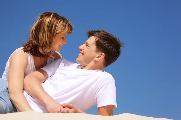 Lachende paar in witte shirts op het strand — Stockfoto