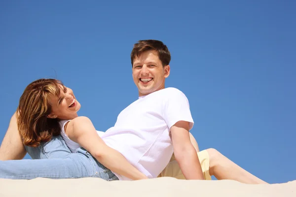Usmívající se dvojice v bílých dresech na pláži — Stock fotografie