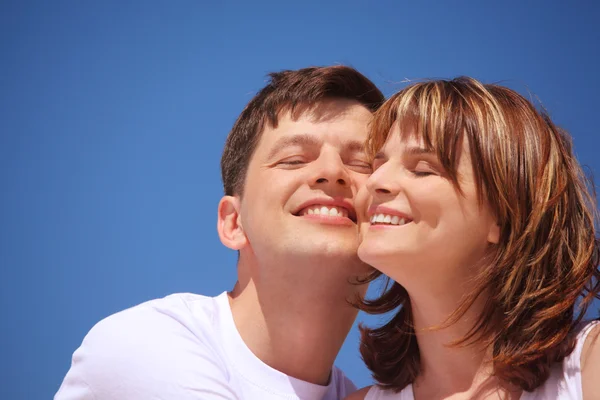 Attractive pair against blue sky, touching by cheeks — Stock Photo, Image