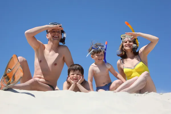 Сім'я з сином лежить на піску з масками для снорлінгу — стокове фото