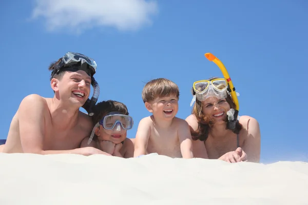 Familia con hijo acostado en la arena con máscaras de snorkel — Foto de Stock