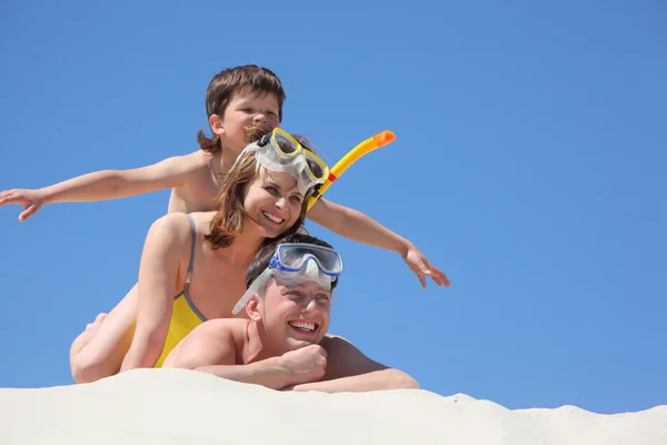 Семья с сыном лежит на песке в масках для подводного плавания — стоковое фото